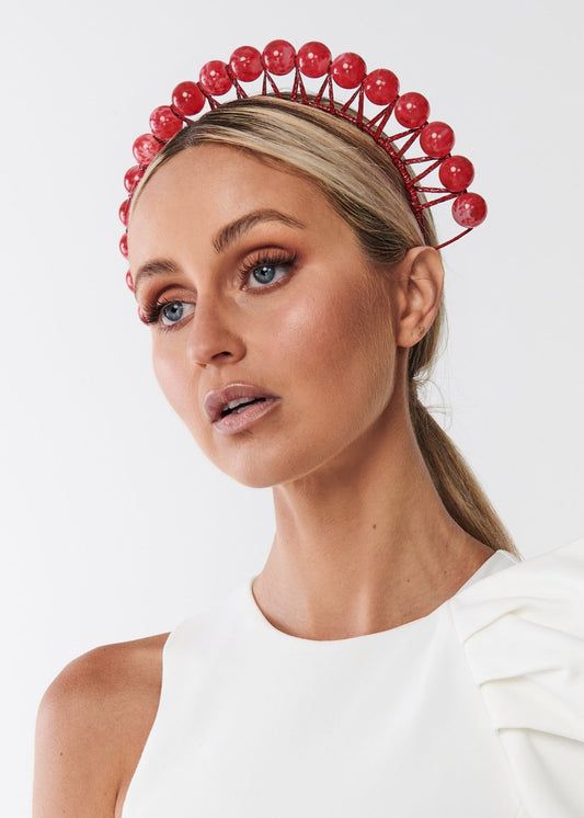 Woman wearing a red beaded headband against a white background