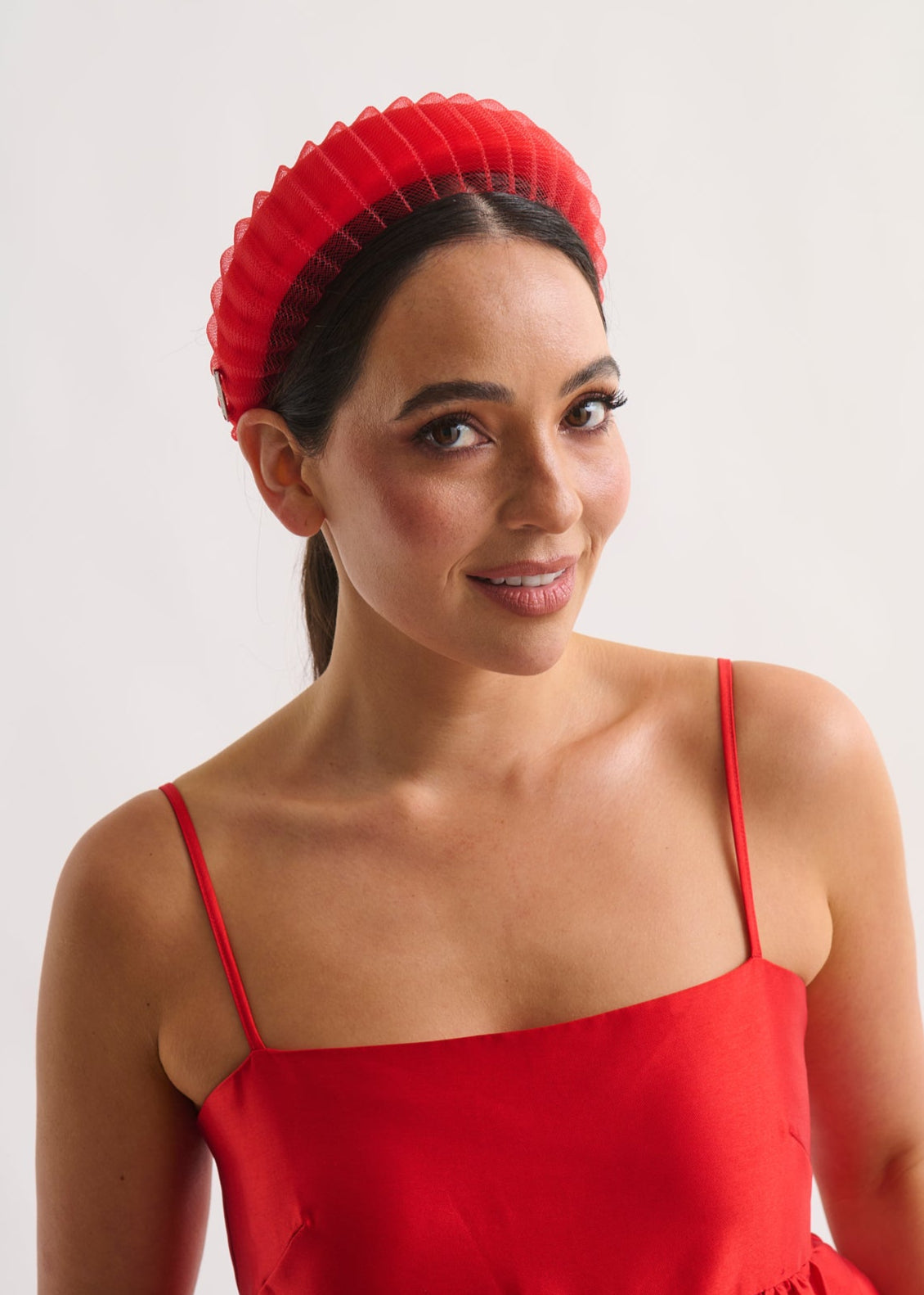 Woman wearing a red dress and headband against a white background