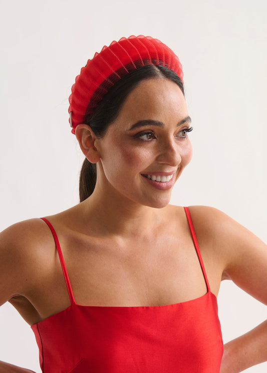 Woman wearing a red dress and headband against a white background