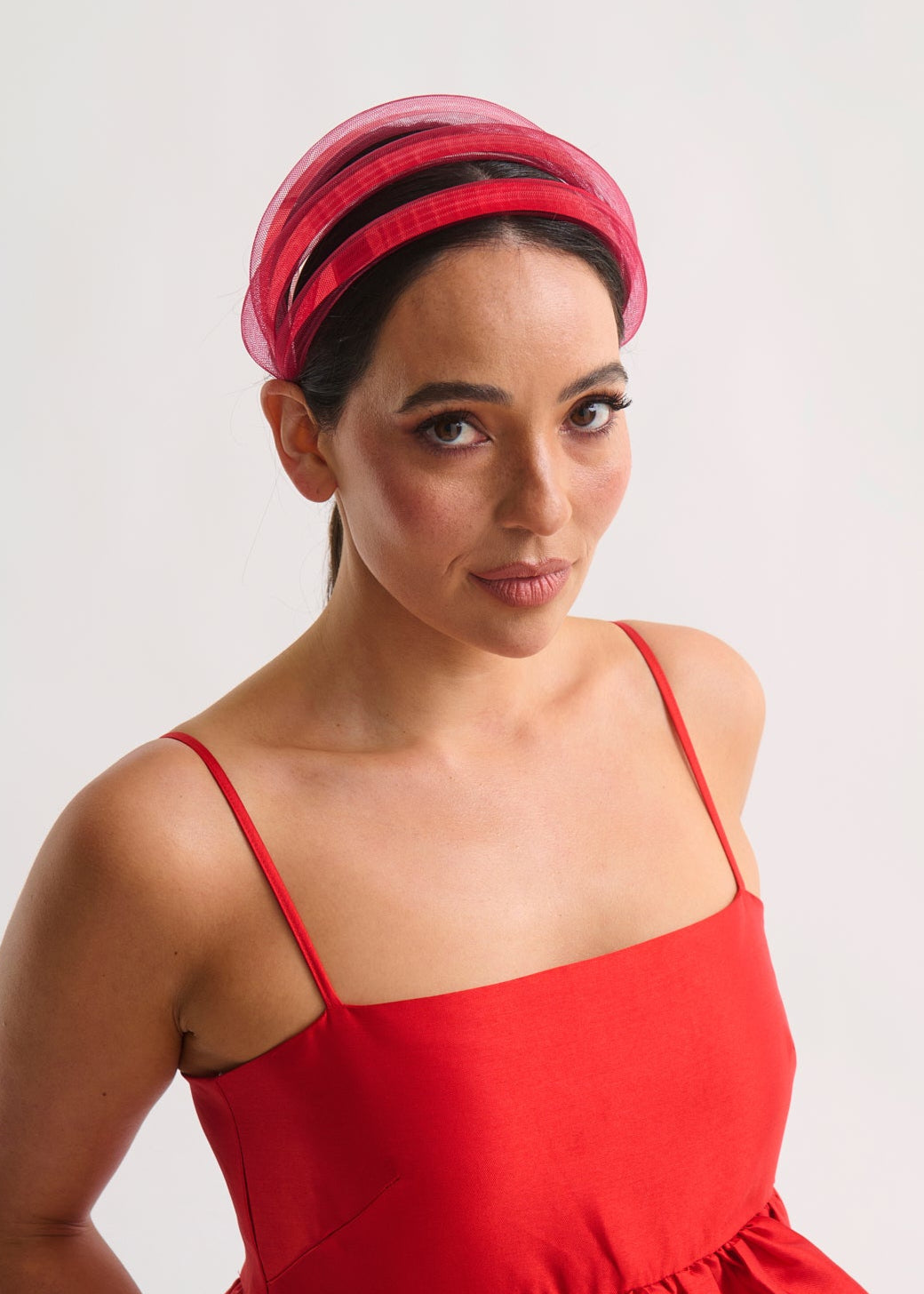 Woman wearing a red dress and headband against a white background