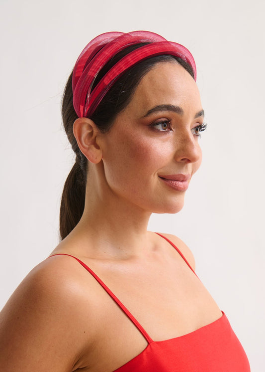 Woman wearing a red headband and red dress against a plain background