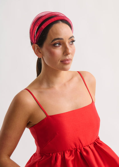 Woman wearing a red dress and headband against a white background