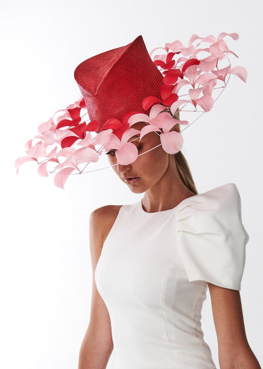Woman wearing a white dress and a red and pink decorative hat on a white background