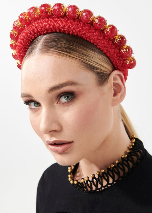 Woman wearing a red beaded headband with gold accents on a white background