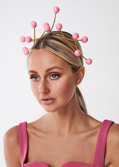 Woman wearing a pink bead headpiece against a white background