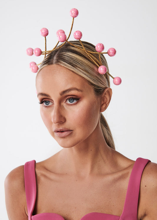 Woman wearing a pink bead headpiece against a white background