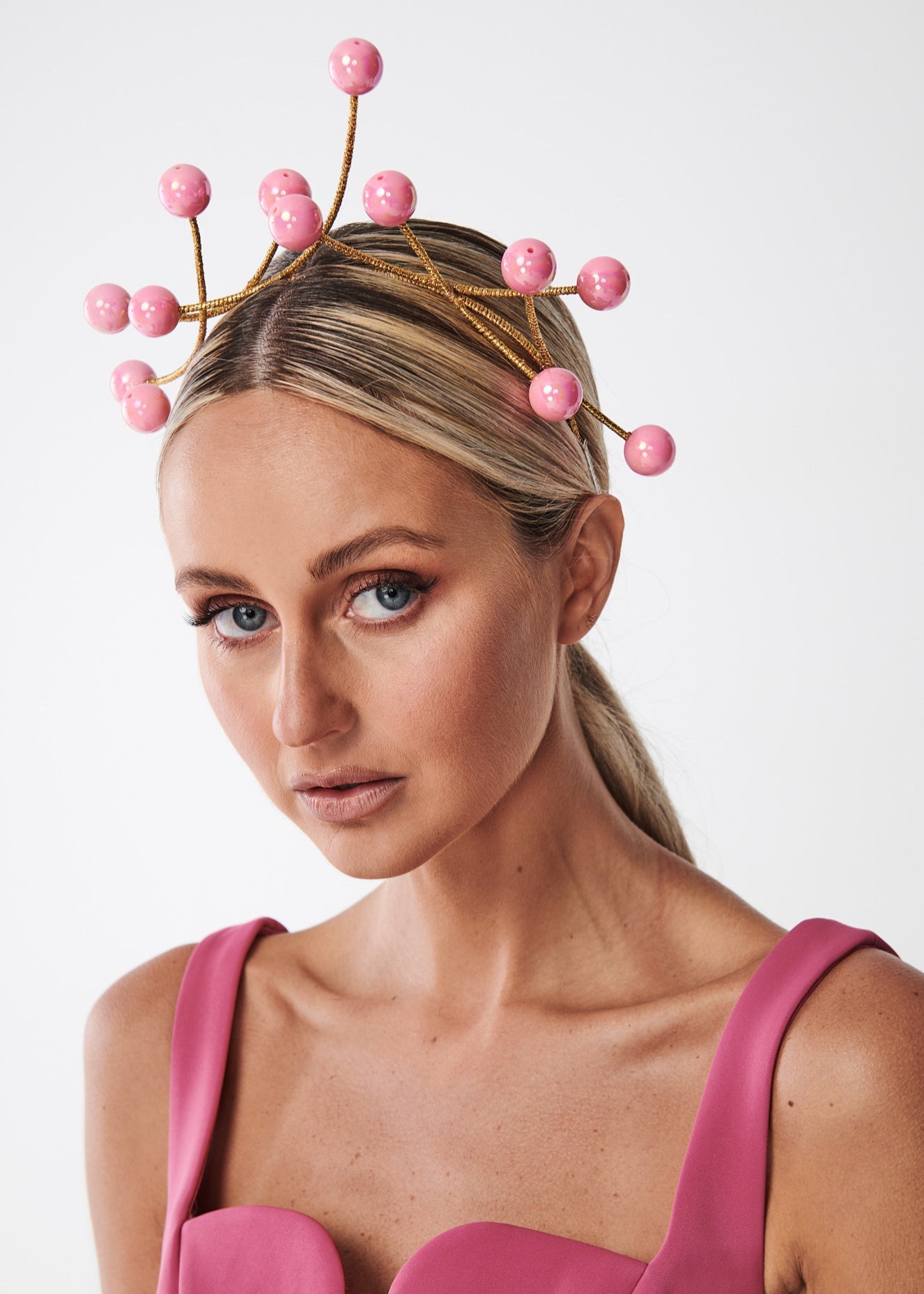 Woman wearing a decorative headpiece with pink beads on a plain background