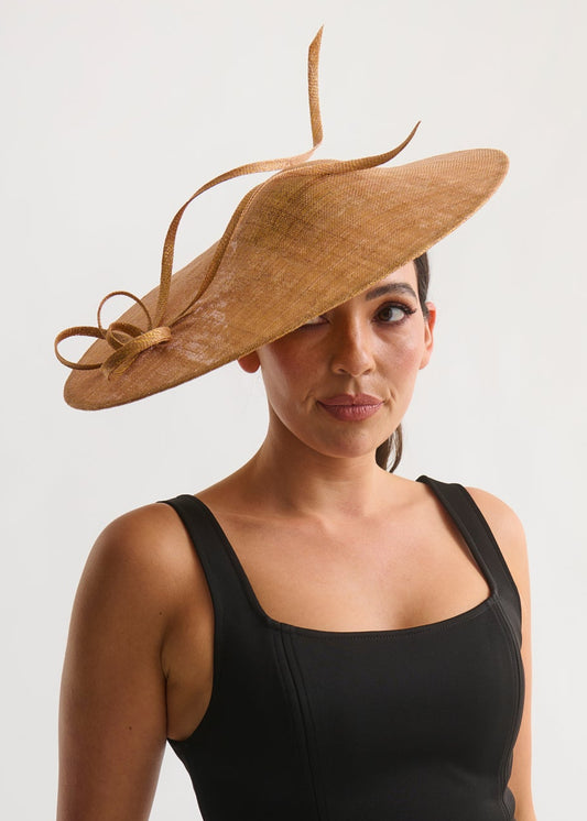 Woman wearing a black dress and a large gold hat on a white background