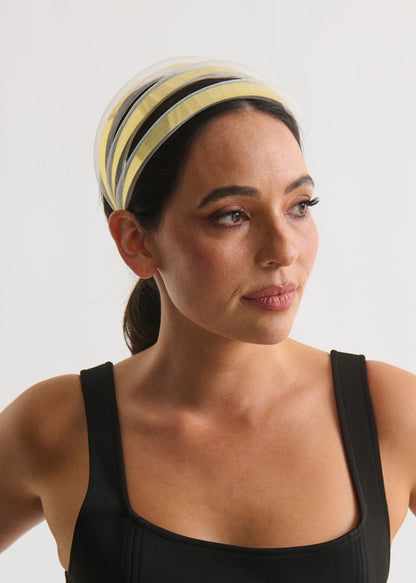 Woman wearing a black tank top and gold headband against a white background