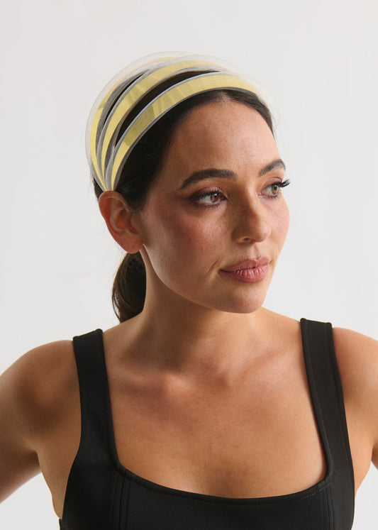 Woman wearing a black tank top and gold headband against a white background
