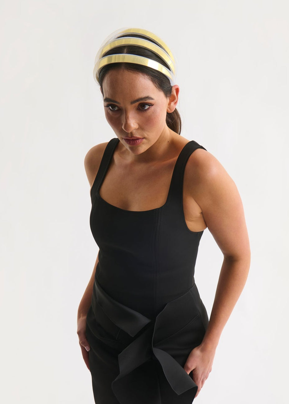 Woman wearing a black dress with a gold headband on a white background