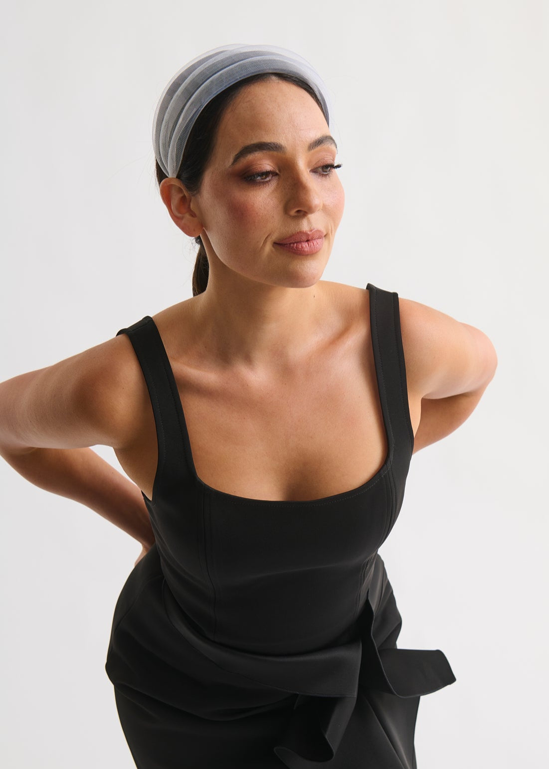 Woman wearing a black dress with a white headband against a white background