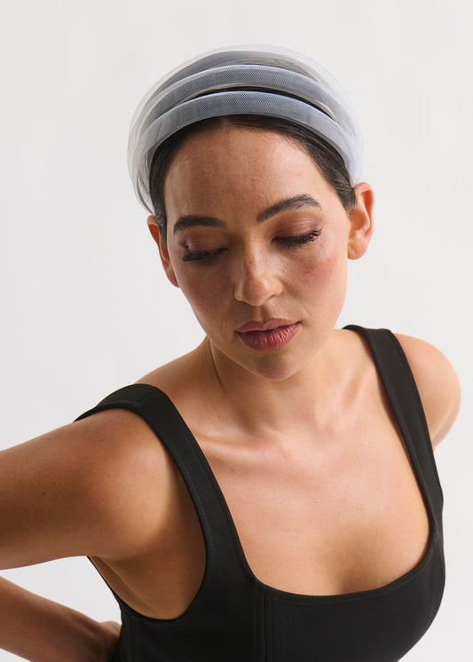Woman wearing a black sleeveless top and white headband on a white background