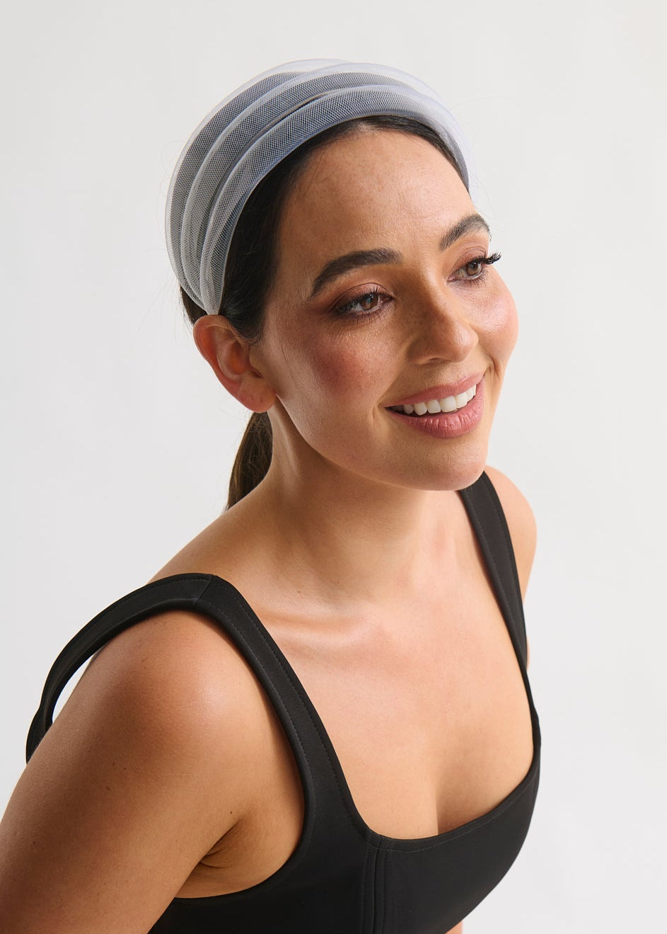 Woman wearing a white headband against a white background