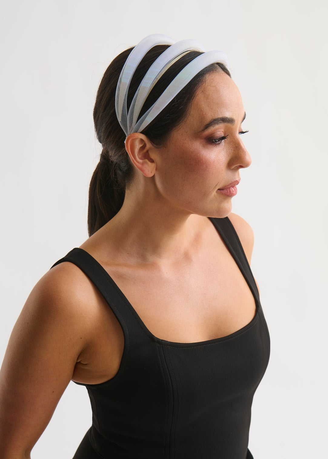 Woman wearing a black tank top and striped headband on a plain background