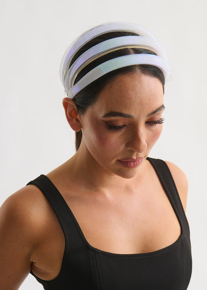 Woman wearing a black tank top and a white striped headband on a plain background