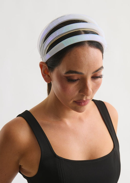 Woman wearing a black tank top and a white striped headband on a plain background