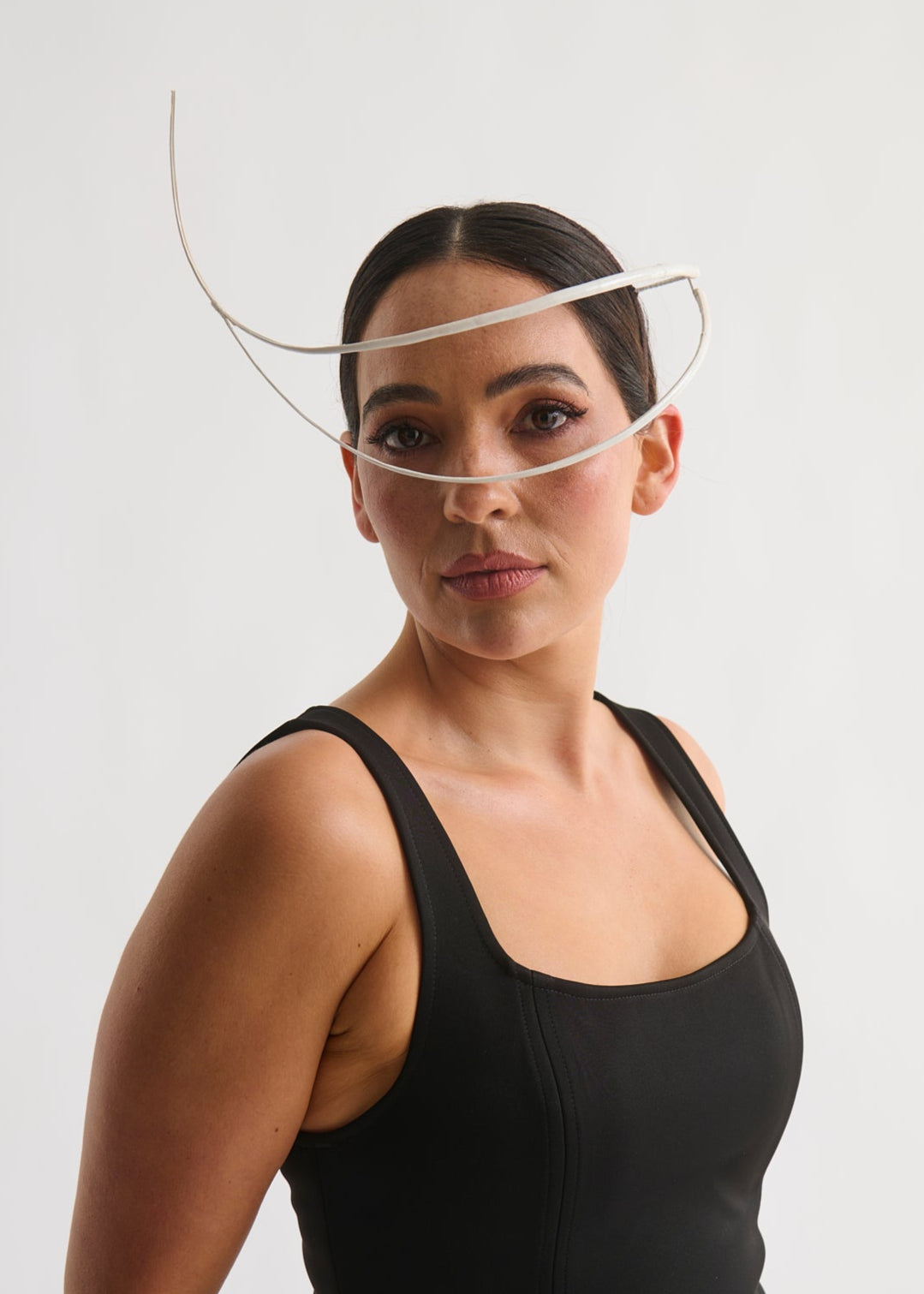 Woman wearing a white feather quill headpiece and a black dress against a white background