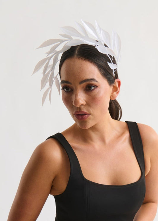 Woman wearing a white leaf headpiece and black dress with a white background