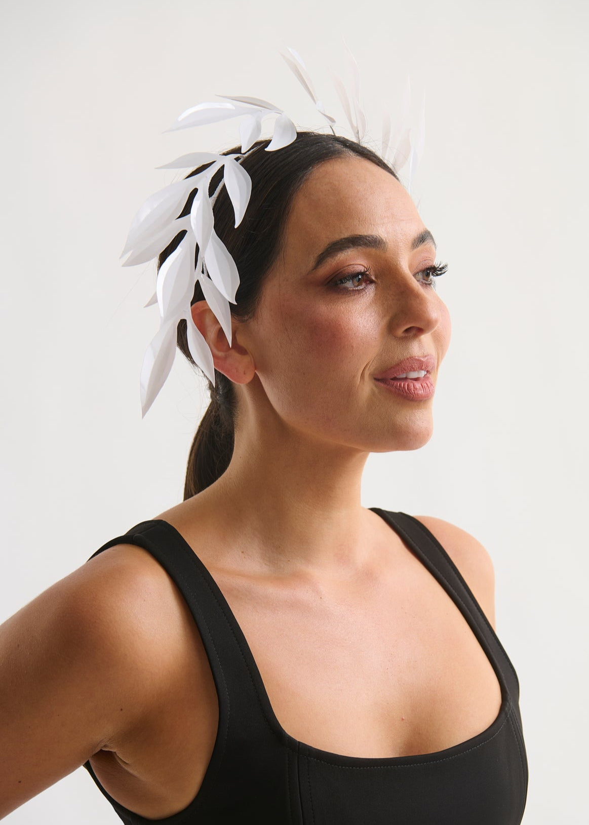Woman wearing a white leaf headpiece and black dress with a white background