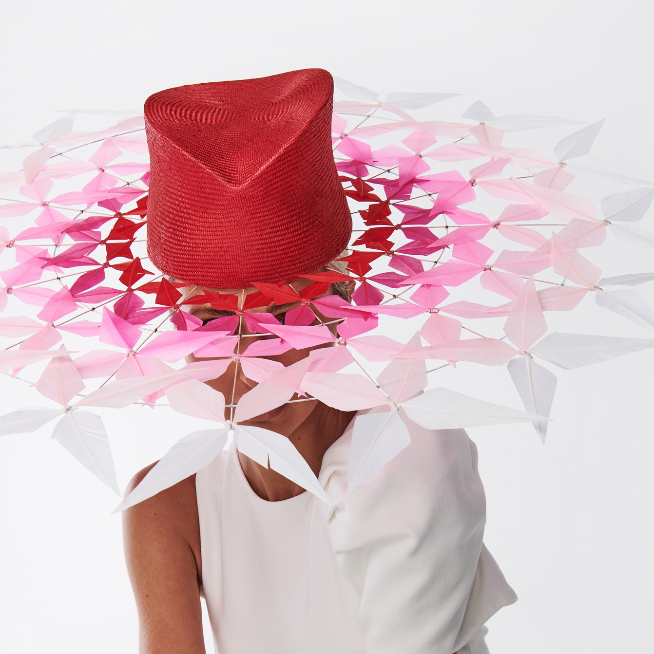 Person wearing a red hat with a pink and white flower-like design on a white background