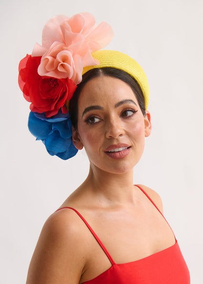 Woman wearing a colorful floral headpiece and red dress against a white background