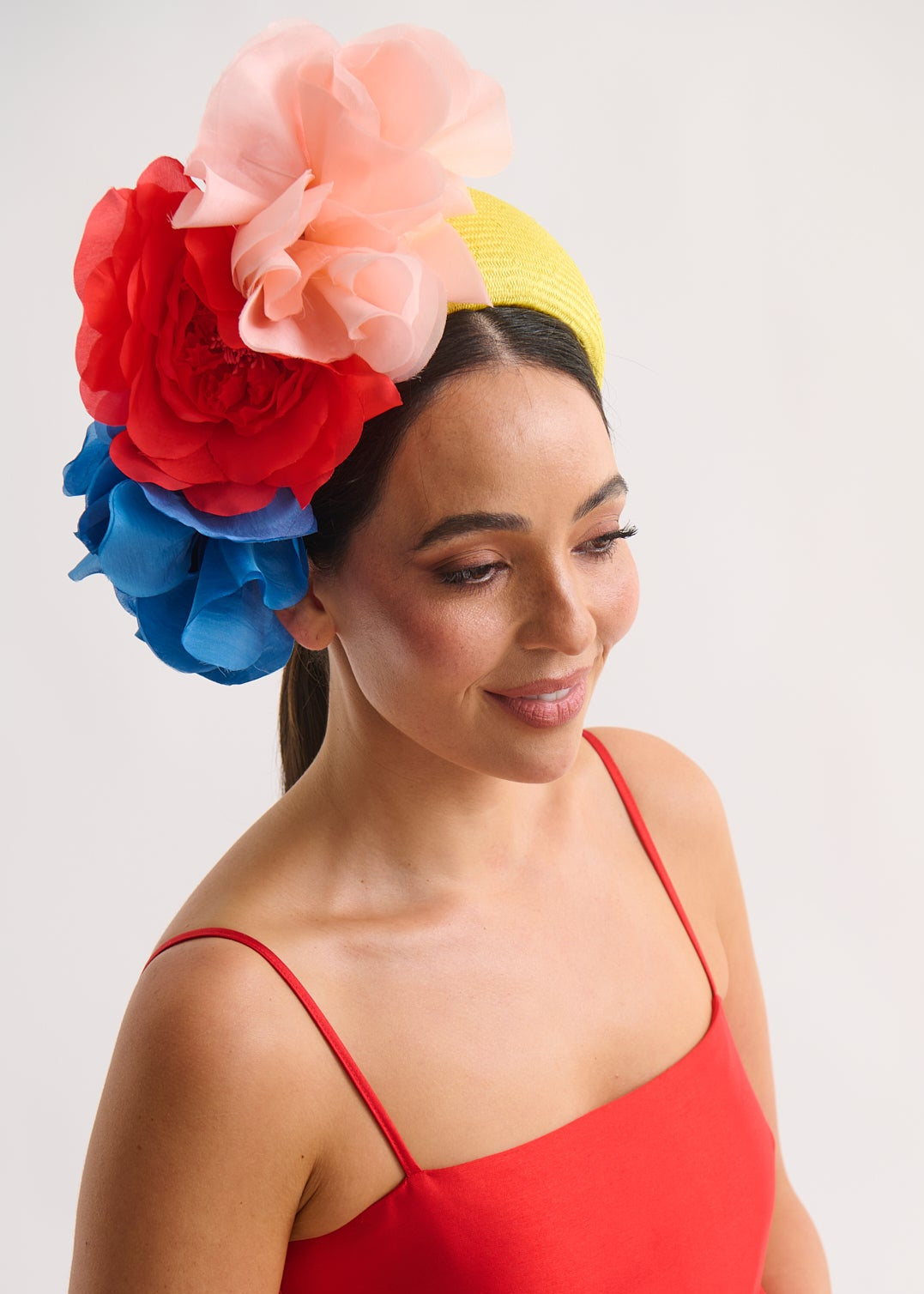 Woman wearing a colorful flower headband and red dress on a white background